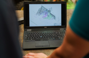 Laptop displaying 3D architectural model in design software for construction project
