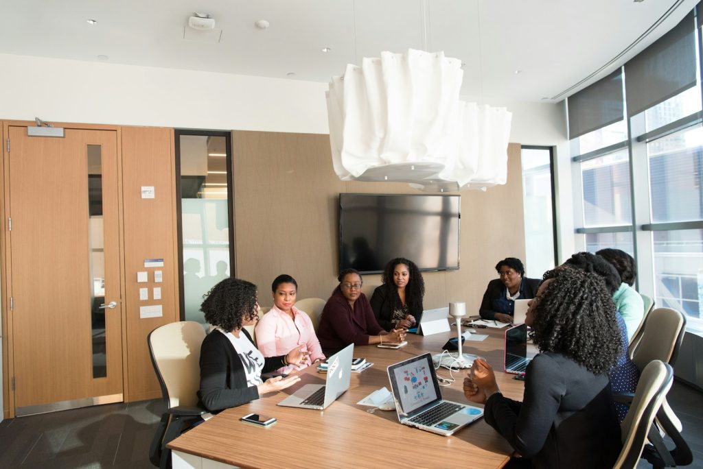 Diverse team collaborates in modern conference room with laptops and technology, discussing project strategy