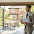 Estate agent in a suit with plans, standing in a modern home with open bifold doors leading to a garden