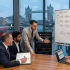 Business meeting discussing supply chain and IT infrastructure with Tower Bridge view in background