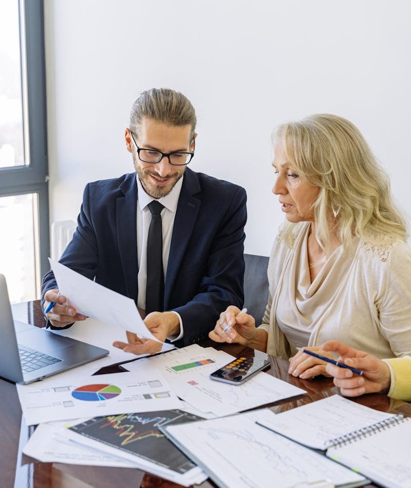 Two business professionals reviewing financial documents and graphs during a meeting